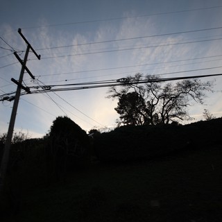 Silhouetted Power Lines at Dusk Over Rural Hillside
