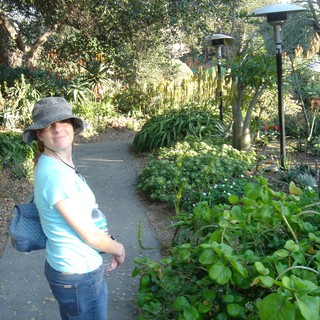 Woman Smiling on Lush Botanical Garden Pathway