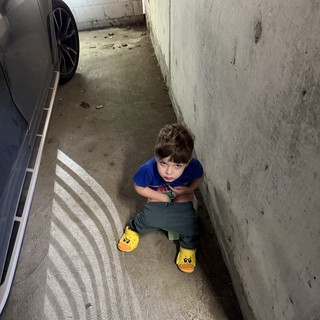 Young Child Sitting in Narrow Parking Garage Space