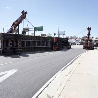 Crane lifting overturned truck on the street