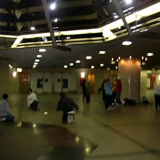 A Group of People Huddle Together on the Airport Floor