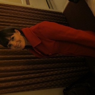 Woman in Red Coat Smiling Over Shoulder Indoors