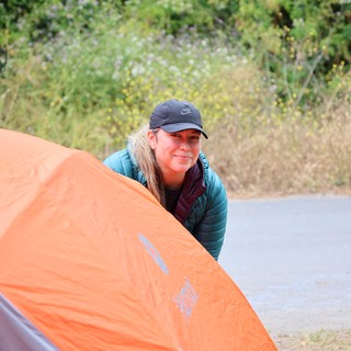 Smiling Camper Setting Up Orange Tent Outdoors