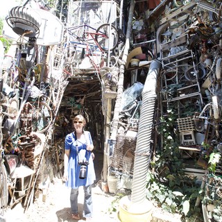Woman Photographer Dwarfed by Cathedral of Junk Austin