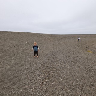 Young Child Smiles on Vast Dark Sand Beach