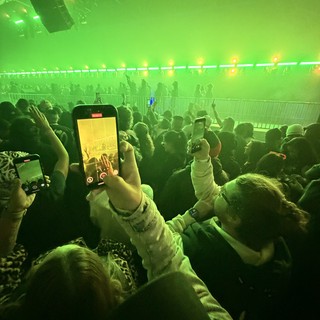 Concert Crowd Recording Performance with Green Stage Lights