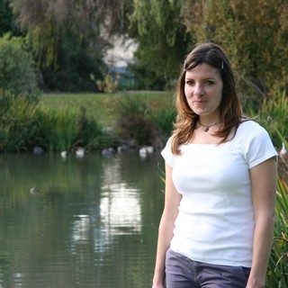 Young Woman Smiling by a Tranquil Park Pond