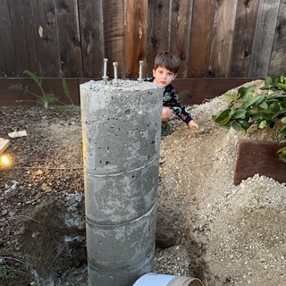 Young Boy Explores Concrete Pier Foundation in Backyard