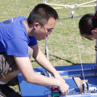 Engineering Duo Works on a Small Device Outdoors