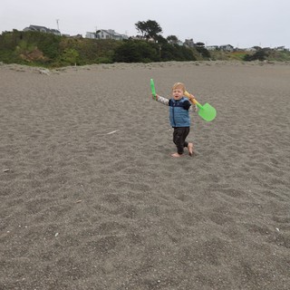 Barefoot Toddler Triumphant with Beach Shovels