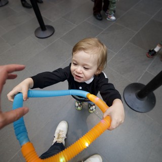 Toddler Playing with Colorful Tubes at Baby Rave Event