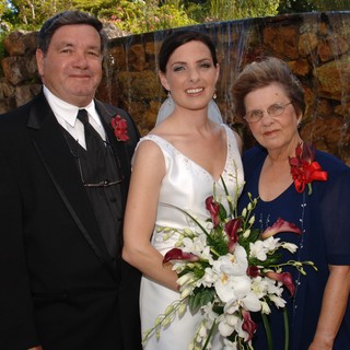 Bride Poses With Parents at Garden Wedding