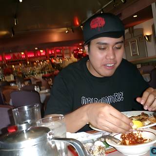 A Man in Black Hat Enjoying a Meal at a Restaurant