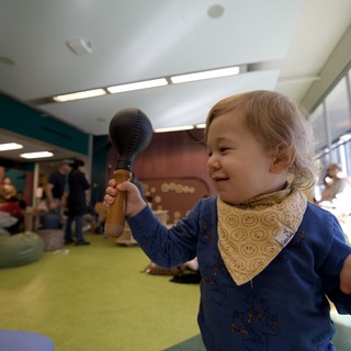 Joyful Toddler Playing with Wooden Toy at Children's Museum