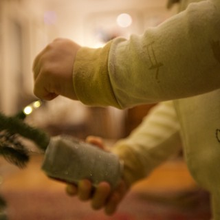 Hands Hanging Glass Ornament on Christmas Tree
