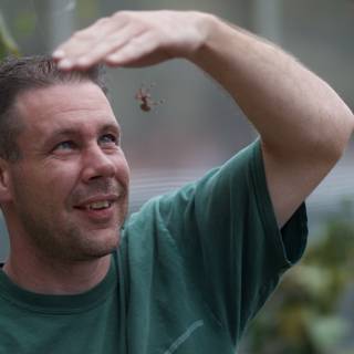 Green shirt man holding a small insect