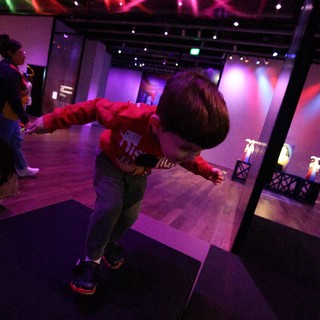 Child Dancing at Baby Rave Event Under Colorful Lights