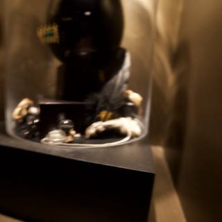 Dark Sculptural Mask Display in Glass Case