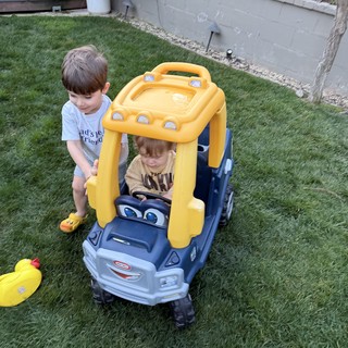 Brothers Playing with Yellow Toy Car in Backyard