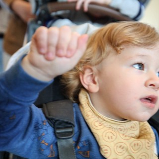 Young Child Waving from Car Seat During Road Trip