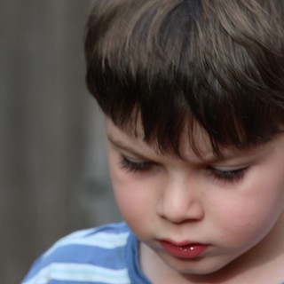 Young Child in Contemplative Moment, Blue Striped Shirt
