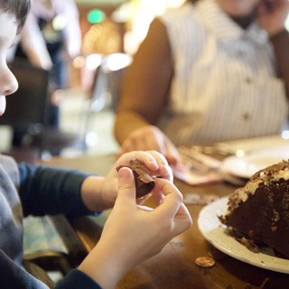 Young Boy Enjoying Chocolate Cake at Family Gathering