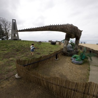 Child Encounters Life-Size Dinosaur Statue at Coastal Park