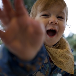 Joyful Toddler Reaching Out at Dinner Table