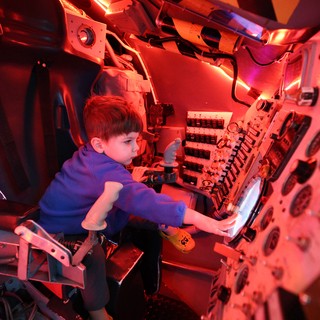 Young Visitor Explores Submarine Control Panel Exhibit