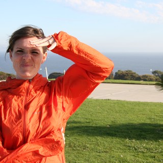 Woman in Orange Jacket Shielding Eyes Oceanside