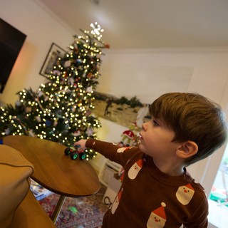 Child Pointing at Illuminated Christmas Tree in Wonder