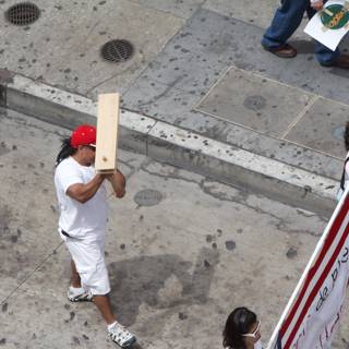 Man Carrying a Wooden Board on City Sidewalk