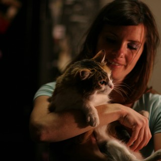 Woman Tenderly Holds Tabby Cat in Dim Light