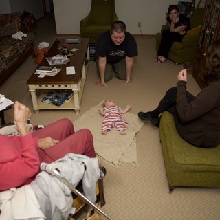 Family Gathering Around Newborn Baby on Floor