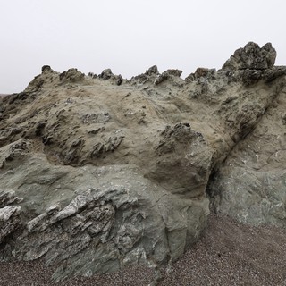 Jagged Coastal Rock Formation on Foggy Beach