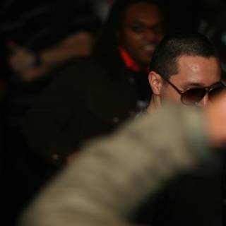 Man in Sunglasses Stands Out in Urban Nightlife Crowd
