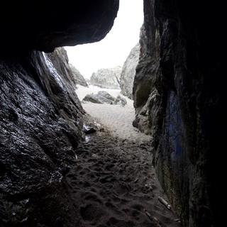Through the Cave: Sandy Beach Beyond Dark Rocks