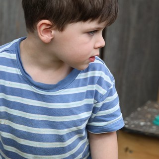 Young Boy in Striped Shirt Observing Outdoors