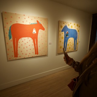 Woman Viewing Contemporary Horse Paintings in Art Gallery