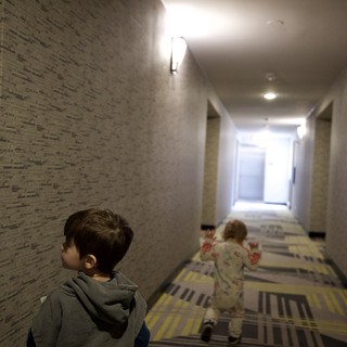 Two Children Running Down Modern Hotel Hallway