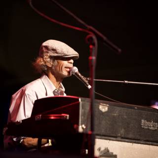 Hat-wearing musician playing keyboard to a crowd