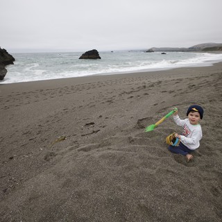 Young Child Playing in Sand at Rocky Coastline