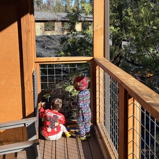 Two Young Children Exploring a Snowy Mountain Cabin Deck