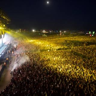 Moonlit Madness Caption: The crowd roars under the night sky at Coachella 2014, as the moon adds a touch of magic to the rock concert atmosphere.