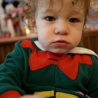 Toddler in Green Elf Costume with Serious Expression
