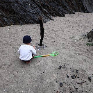 Young Child Explores Rocky Beach with Toy Shovel