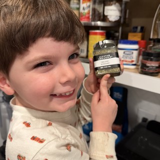 Young Boy Holding Organic Rosemary in Kitchen