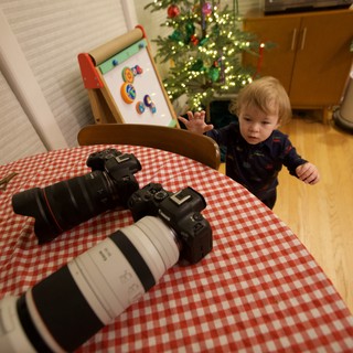 Young Child Reaching for Professional Camera Equipment at Christmas