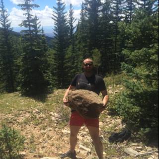 Man holding a large rock in the wilderness