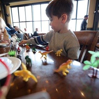 Children Playing with Dinosaur Toys at Restaurant Table